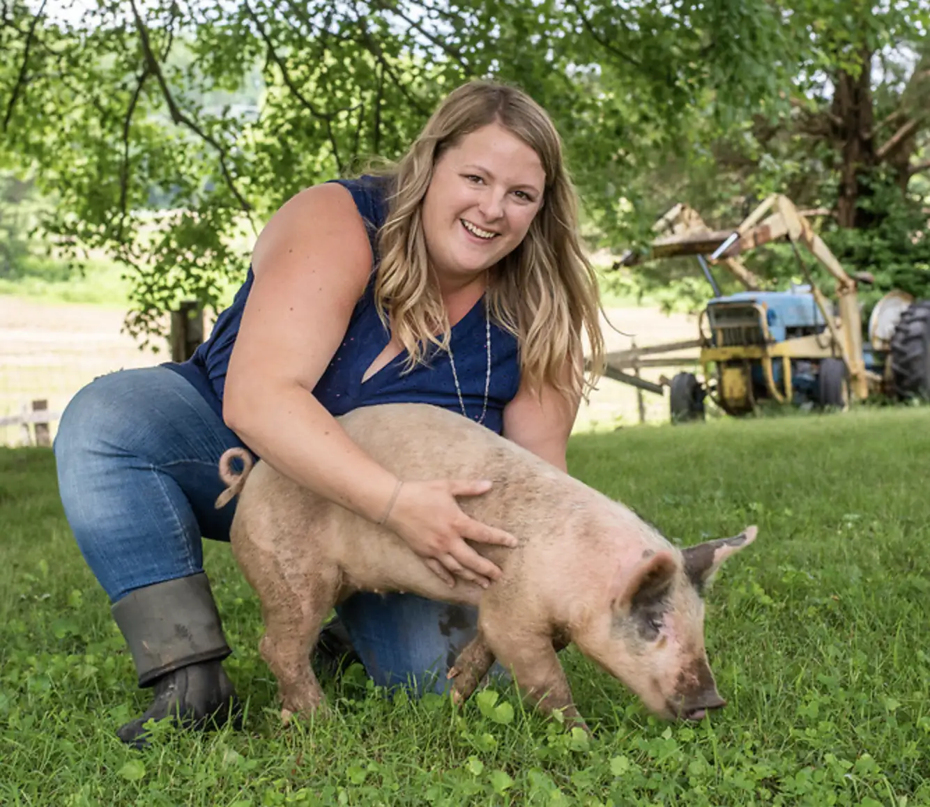 Young person smiling and standing in a doorway holding a piglet